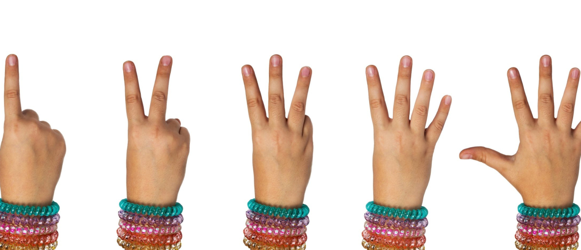 Child's hand shows the numbers one, two, three, four, five on a white background