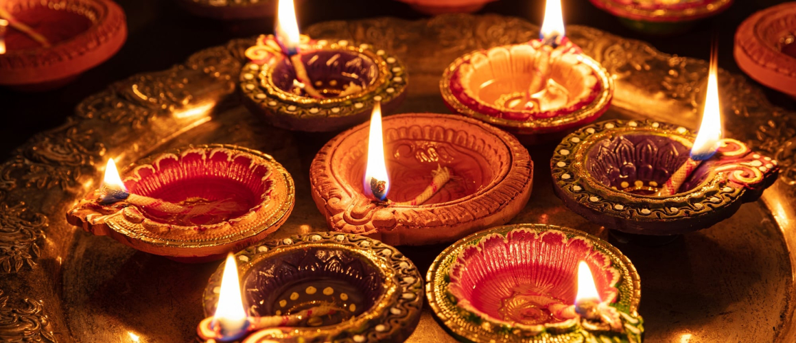 Happy Diwali. Clay diya candles illuminated in Dipavali, Hindu festival of lights. Traditional oil lamps on dark background, banner, closeup view